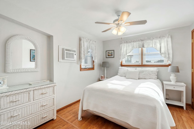 bedroom with a wall mounted AC, ceiling fan, and light wood-type flooring