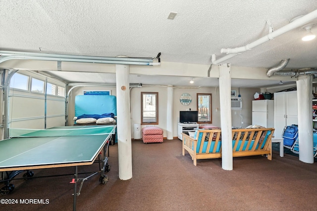 playroom with a wall unit AC, a wealth of natural light, dark carpet, and a textured ceiling