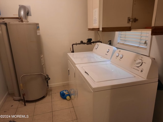 washroom with water heater, washer and clothes dryer, light tile patterned floors, and cabinets