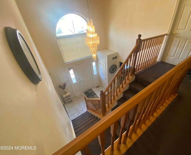 entryway featuring tile patterned floors, a high ceiling, and an inviting chandelier