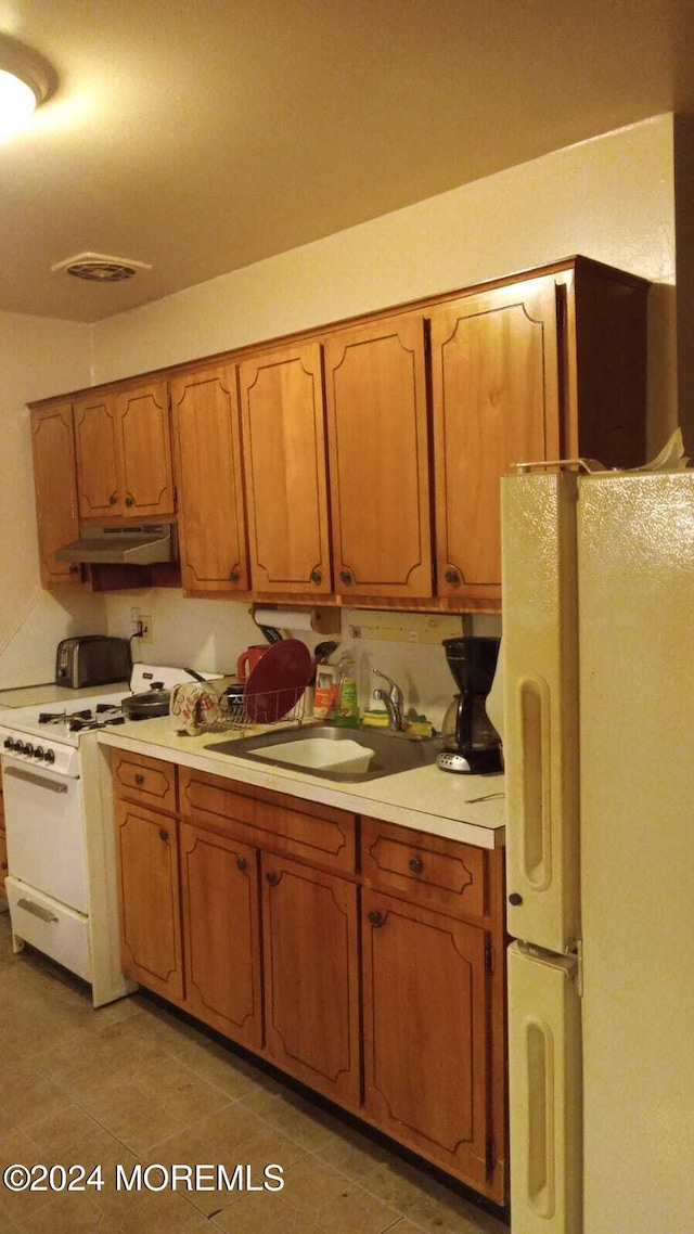 kitchen featuring light tile patterned floors, white appliances, and sink