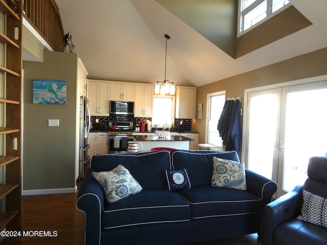 living room featuring dark hardwood / wood-style flooring, high vaulted ceiling, and a notable chandelier