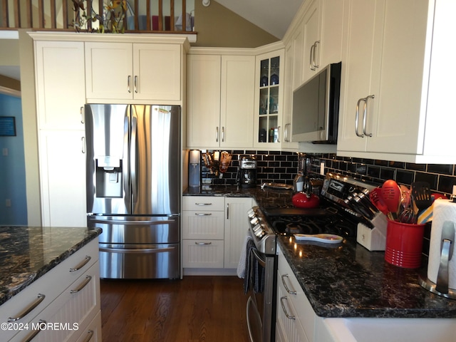 kitchen featuring backsplash, white cabinets, vaulted ceiling, dark hardwood / wood-style floors, and appliances with stainless steel finishes