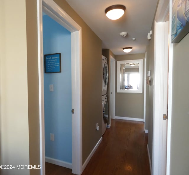 hall featuring stacked washer / dryer and dark wood-type flooring