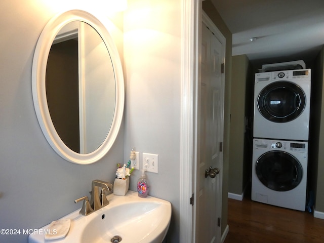 bathroom featuring hardwood / wood-style floors, stacked washer / drying machine, and sink