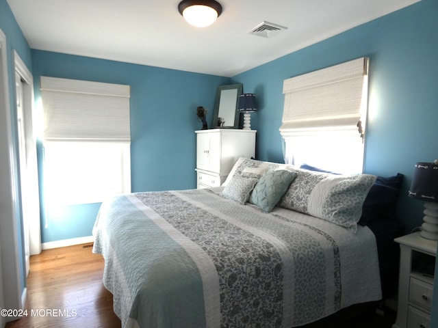 bedroom with hardwood / wood-style flooring and multiple windows