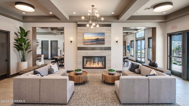 living room with beamed ceiling, a tile fireplace, and a chandelier