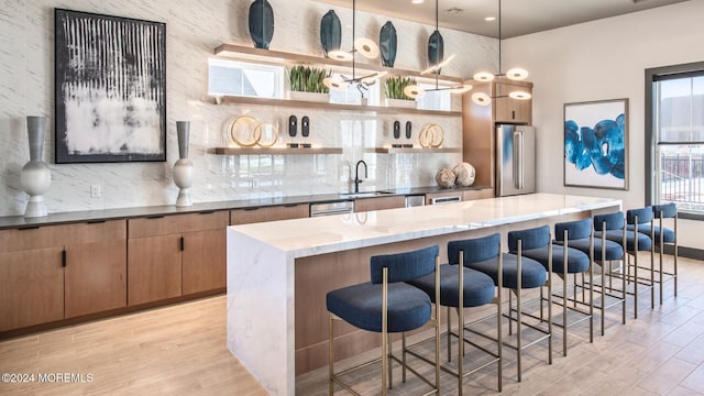 kitchen featuring a kitchen breakfast bar, high end fridge, a kitchen island, and hanging light fixtures