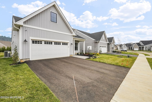 view of front of home with cooling unit, a garage, and a front yard