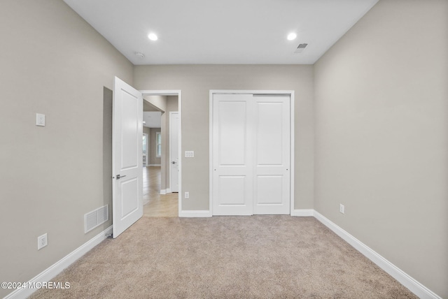 unfurnished bedroom with light carpet and a closet