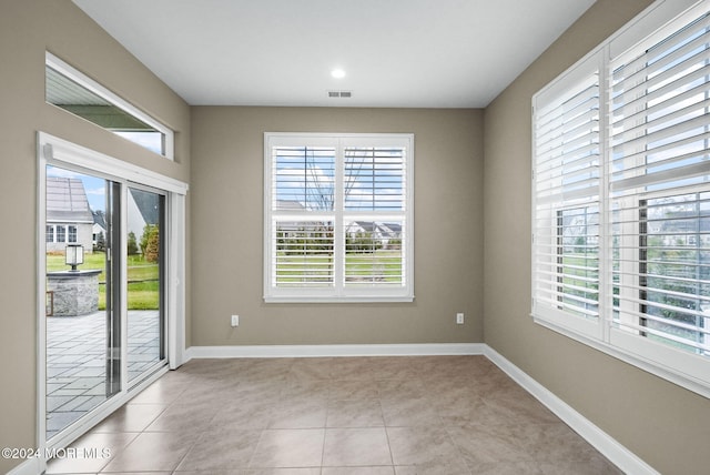 tiled spare room featuring a wealth of natural light