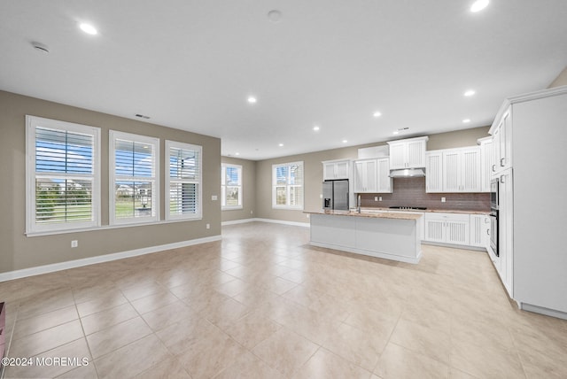 kitchen featuring stainless steel fridge, a center island with sink, extractor fan, and a healthy amount of sunlight