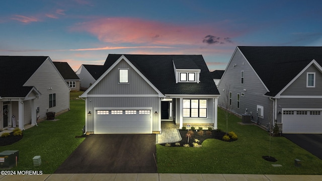 view of front facade featuring central AC unit, a garage, and a yard