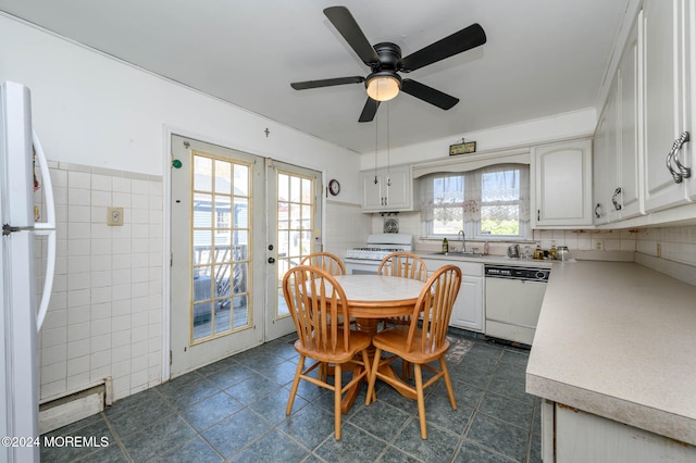 dining room featuring french doors, dark tile patterned floors, ceiling fan, and tile walls