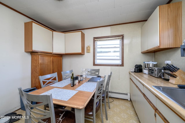 dining room with baseboard heating, ornamental molding, and sink