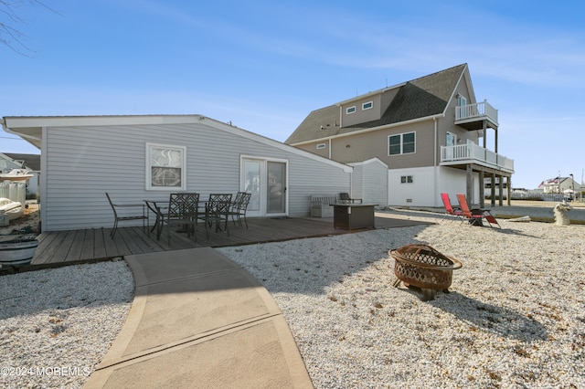 back of house with a balcony, an outdoor fire pit, and a wooden deck