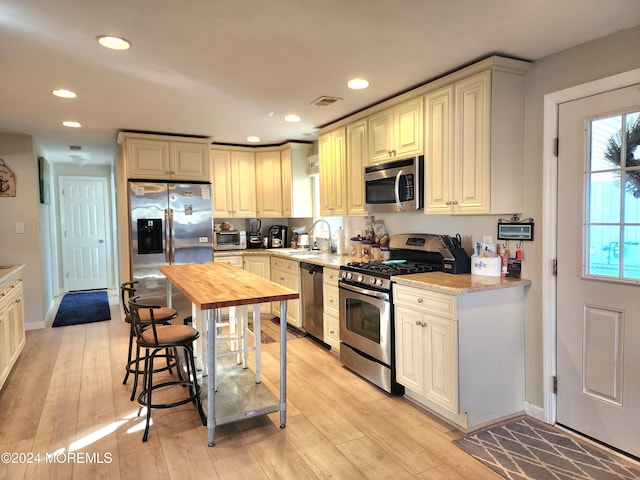 kitchen featuring light hardwood / wood-style floors, light stone counters, sink, and appliances with stainless steel finishes