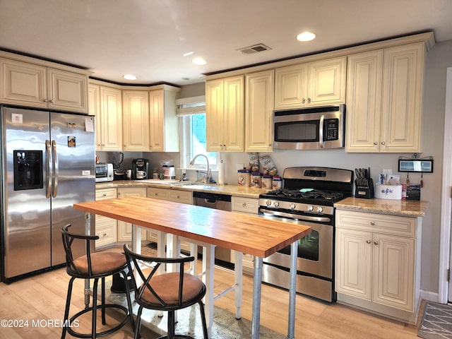 kitchen featuring butcher block countertops, light hardwood / wood-style flooring, stainless steel appliances, and sink