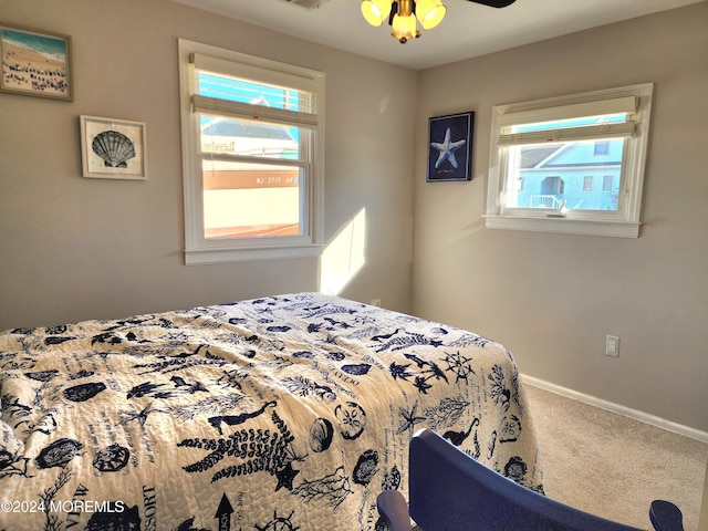 carpeted bedroom with ceiling fan and multiple windows