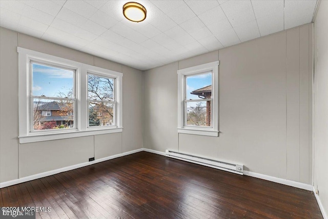 unfurnished room featuring hardwood / wood-style floors and a baseboard heating unit