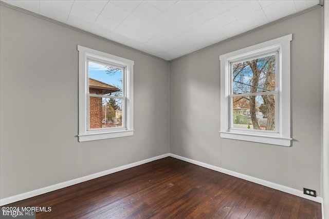 empty room featuring hardwood / wood-style flooring, plenty of natural light, and ornamental molding