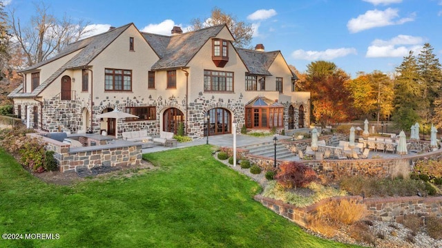 rear view of house featuring a lawn, french doors, and a patio