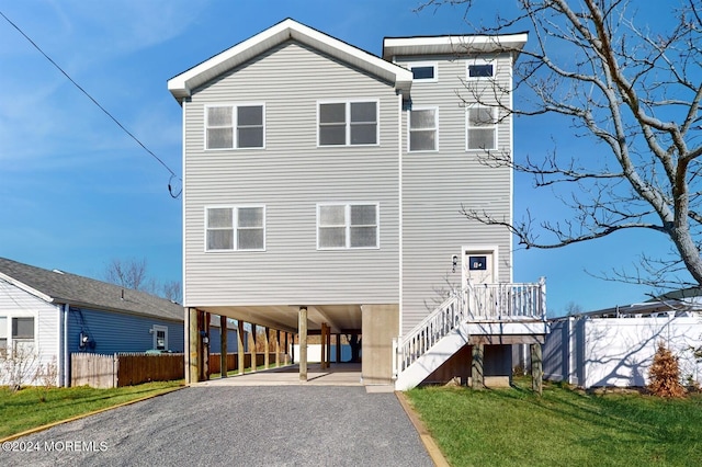 view of front of house with driveway, stairway, fence, a carport, and a front yard