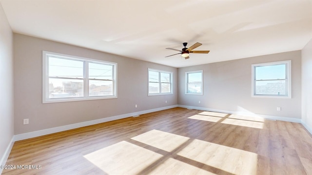 spare room with a ceiling fan, light wood-style flooring, and baseboards