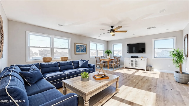 living room with a ceiling fan, visible vents, baseboards, and wood finished floors