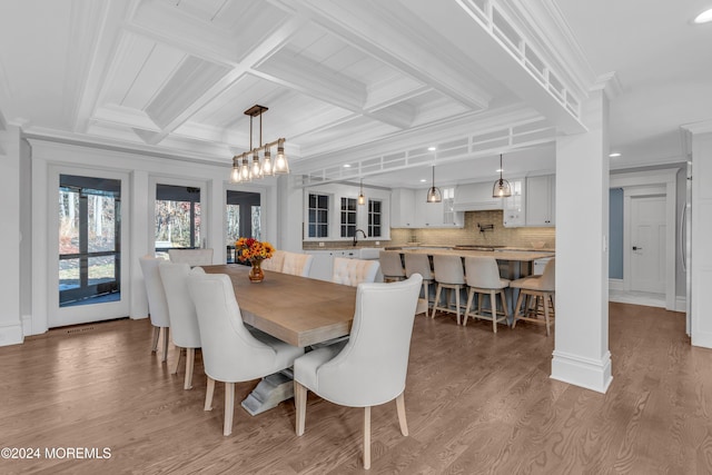 dining room with ornamental molding, hardwood / wood-style flooring, coffered ceiling, and sink