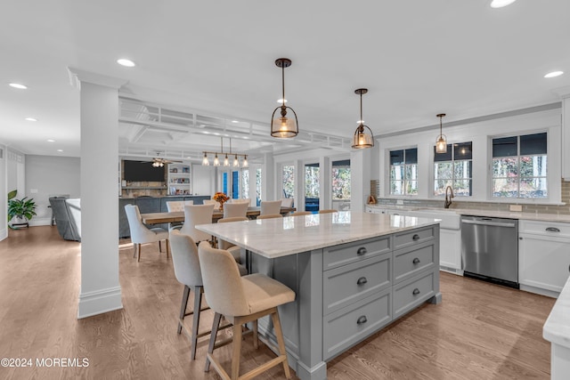 kitchen featuring a center island, hanging light fixtures, stainless steel dishwasher, ceiling fan, and light hardwood / wood-style floors