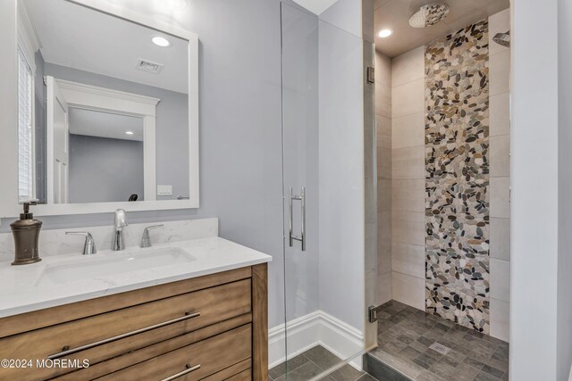 bathroom with a shower with door, vanity, and tile patterned flooring