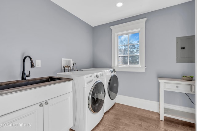 washroom featuring sink, cabinets, light hardwood / wood-style flooring, independent washer and dryer, and electric panel