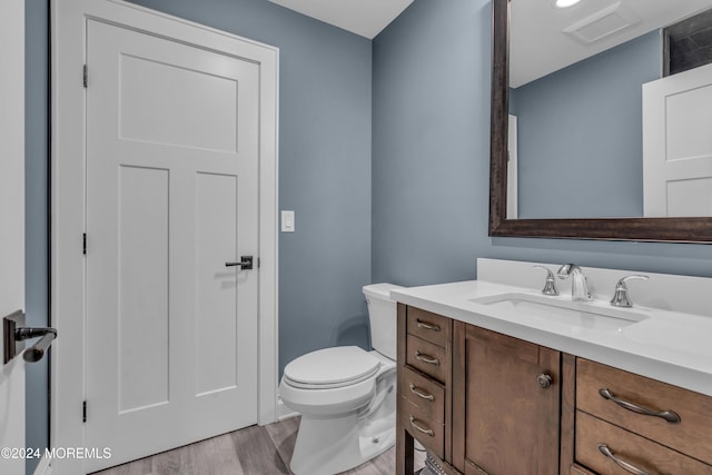 bathroom with toilet, vanity, and hardwood / wood-style flooring