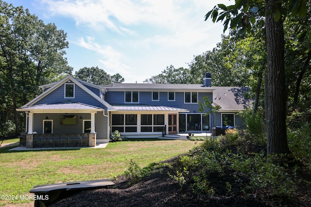 rear view of property with a lawn, a sunroom, and an outdoor bar