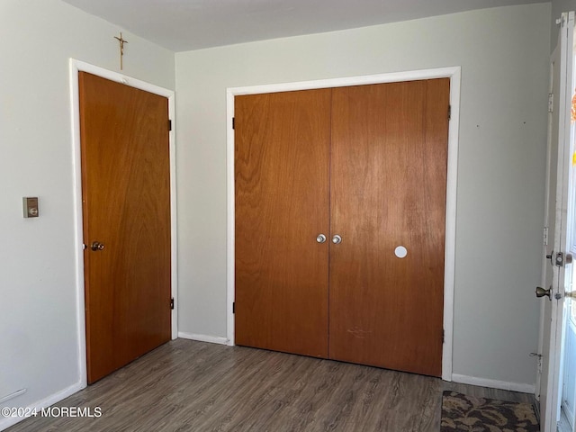 unfurnished bedroom featuring dark wood-type flooring and a closet