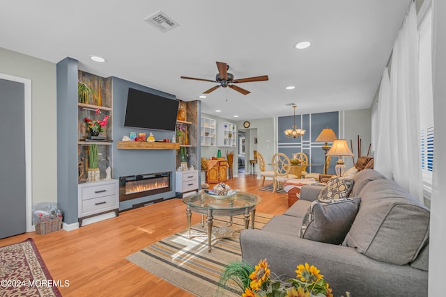 living room featuring ceiling fan with notable chandelier and wood-type flooring