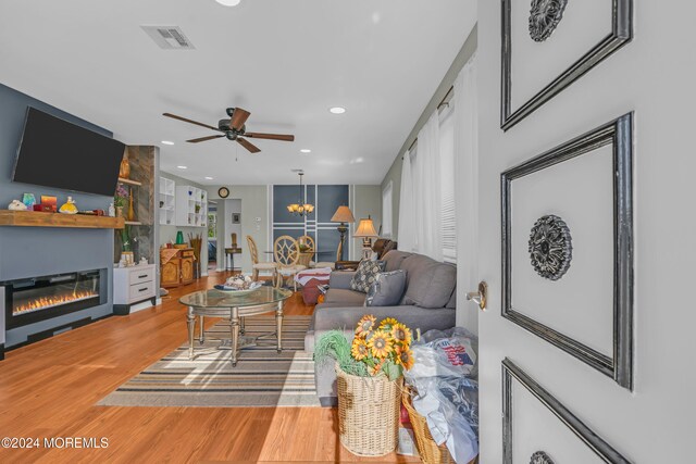 living room with hardwood / wood-style floors, a large fireplace, and ceiling fan