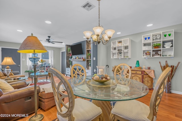 dining space with ceiling fan with notable chandelier and light hardwood / wood-style floors