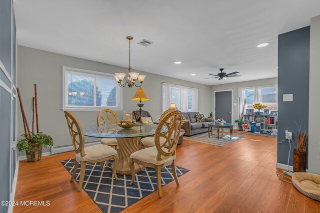 dining area with ceiling fan with notable chandelier, light wood-type flooring, and a baseboard radiator