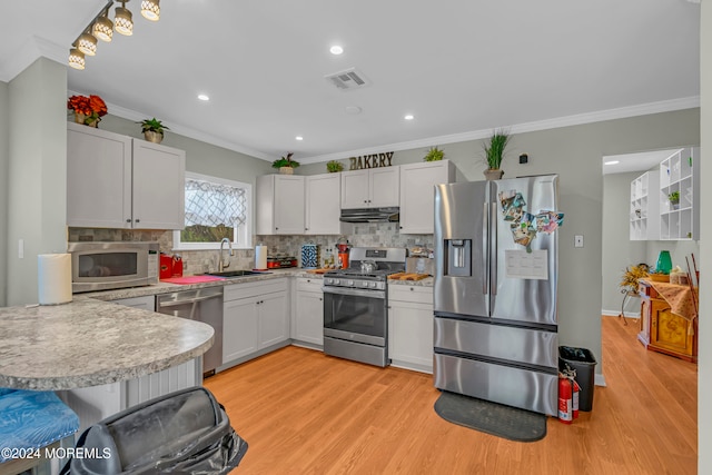 kitchen featuring white cabinetry, sink, stainless steel appliances, crown molding, and light hardwood / wood-style floors