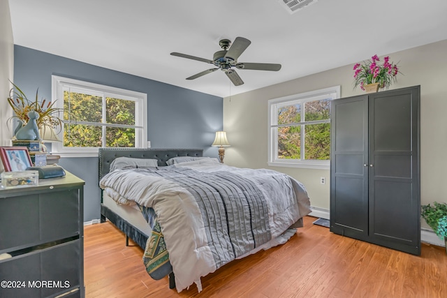 bedroom with light wood-type flooring, multiple windows, and ceiling fan