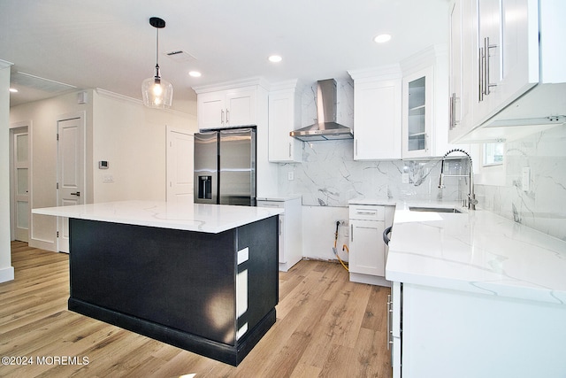 kitchen featuring white cabinets, wall chimney exhaust hood, a kitchen island, and stainless steel fridge with ice dispenser