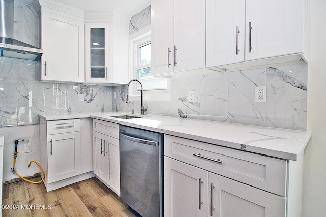 kitchen featuring white cabinets, sink, stainless steel dishwasher, and wall chimney range hood