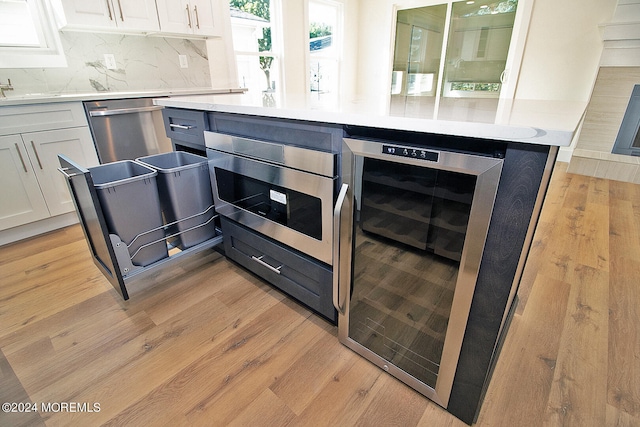 kitchen featuring white cabinetry, dishwasher, beverage cooler, and light hardwood / wood-style floors