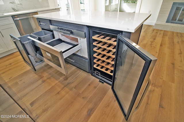 interior space with stainless steel dishwasher, light hardwood / wood-style floors, light stone countertops, and backsplash