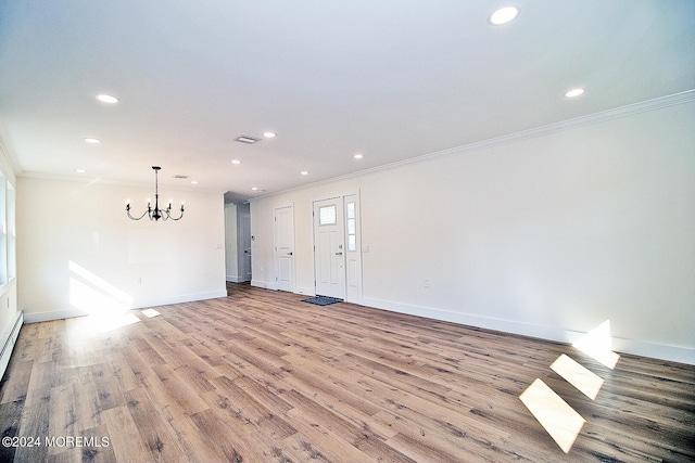 empty room featuring a chandelier, light hardwood / wood-style floors, and crown molding