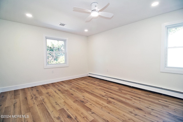 spare room with ceiling fan, plenty of natural light, hardwood / wood-style floors, and a baseboard heating unit