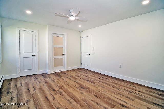 unfurnished bedroom featuring hardwood / wood-style floors, ceiling fan, and a baseboard heating unit