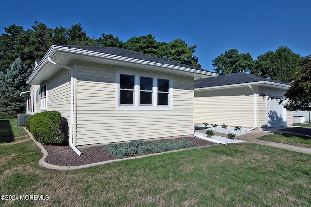 view of side of property featuring a garage, a yard, and central air condition unit